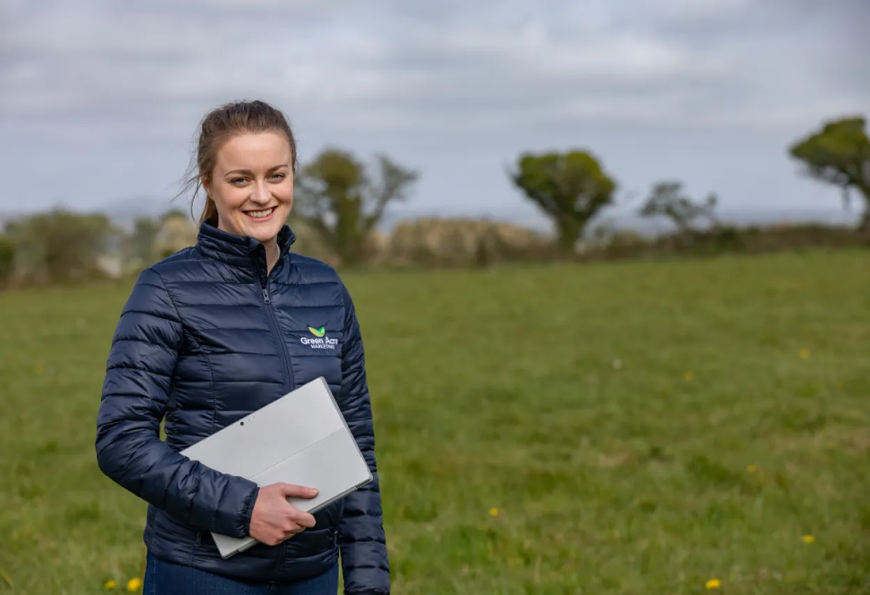 Woman standing in a field holding a laptop